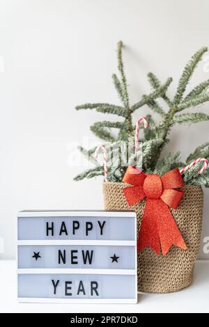 Happy New Year on vintage lightbox with New Years Eve decoration, concept image. Nobilis in a basket of candies. Stock Photo