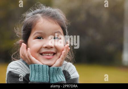 Ive been waiting all day to play. an adorable little girl standing alone in the park and feeling excited. Stock Photo