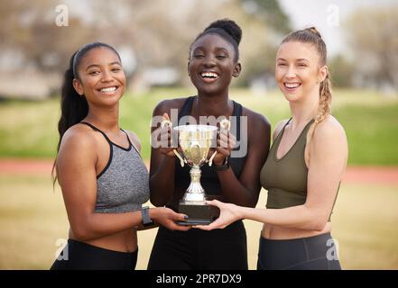 Its all about lifting the trophy. Cropped portrait of three attractive young female athletes celebrating their victory. Stock Photo