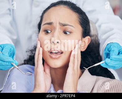 So many sharp objects. Shot of a young woman looking afraid at her dentists office. Stock Photo
