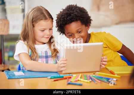 Kids love to learn. Shot of two preschool students looking at something on a digital tablet together. Stock Photo