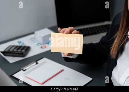 Businesswoman Holding Note With Important Message With One Hand. Woman Having Notebook With Crutial Information. Executive Showing Critical Data On Paper Stock Photo