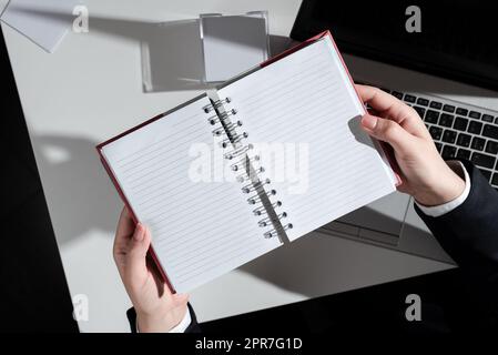 Businesswoman Holding Notebook With New Ideas Over Desk With Notes And Lap Top. Woman In Suit Having Notepad With Important Messages Above Table With Memos And Computer. Stock Photo