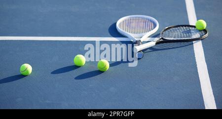 Is that health calling your name. Shot of two tennis rackets and tennis balls on a court during the day. Stock Photo