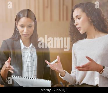 Your ideas are brilliant. two businesswomen working together while using a digital tablet. Stock Photo