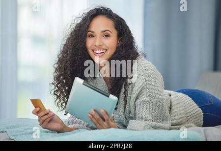Online payments are so simple now. a young woman using her digital tablet to make online card payments. Stock Photo