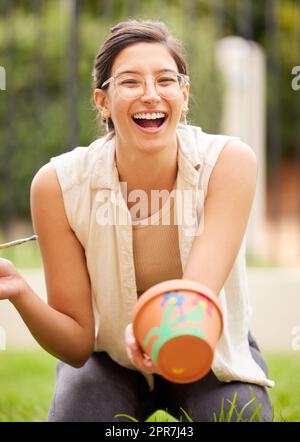When creativity blossoms, thinking emanates. s young woman painting a pot in the garden at home. Stock Photo