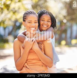 Portrait happy young woman and her daughter spending quality time together in the park during summer. Cute little girl and her beautiful mother bonding outdoors. A lady and her adorable child Stock Photo