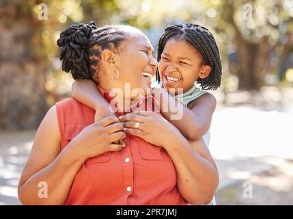 Happy mature woman and her granddaughter spending quality time together outside in the park during summer. Cute little girl and her grandmother bonding outdoors. A granny and her grandchild smiling Stock Photo