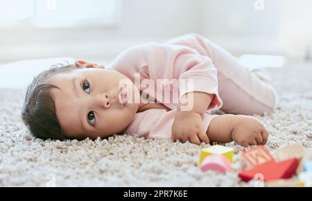 I think Ill nap right here. an adorable baby girl lying on the floor at home. Stock Photo