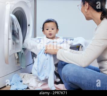 Mom always has time for fun. a young mother playfully bonding with her baby girl while doing the laundry at home. Stock Photo