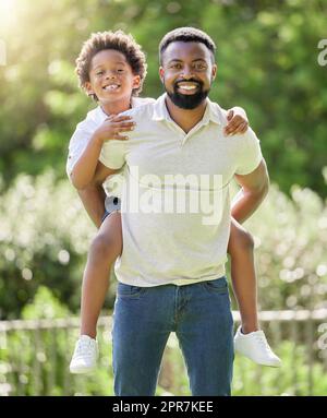My son is a blessing to me. Portrait of a father giving his son a piggyback ride outdoors. Stock Photo