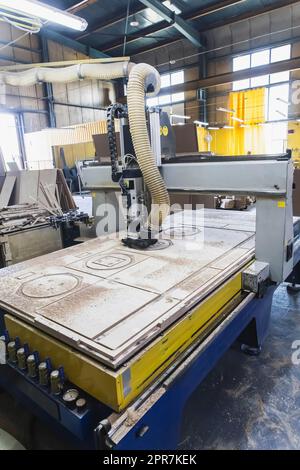 large cnc machine cuts blanks of various shapes on a plywood sheet Stock Photo