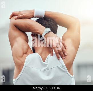 Rear view of unknown mixed race tennis player stretching arm and getting ready for court game. Hispanic fit athlete standing alone and holding stretch as warmup before match. Sporty man in sports club Stock Photo