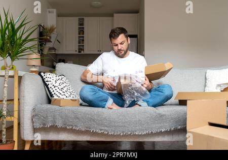 Man unpacking postal parcel, not eco-friendly package. Stock Photo