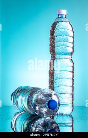 Two plastic cold bottles of water with water drops on blue background. Stock Photo