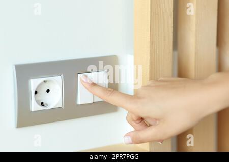 Woman hand pressing light switch Stock Photo