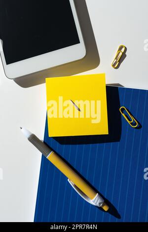 Sticky Note With Important Message On Desk With Pen, Mobile Phone And Paperclips. Crutial Information Presented On Memo On Table With Cellphone And Clips. Stock Photo
