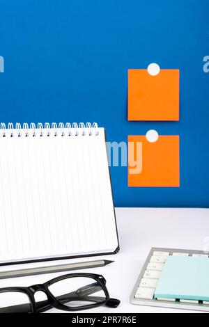 Important Message Written On Notebook On Desk With Pencil, Keyboard, Note And Glasses. Crutial Informations Presented On Notepad On Table With Memos On Wall. Stock Photo