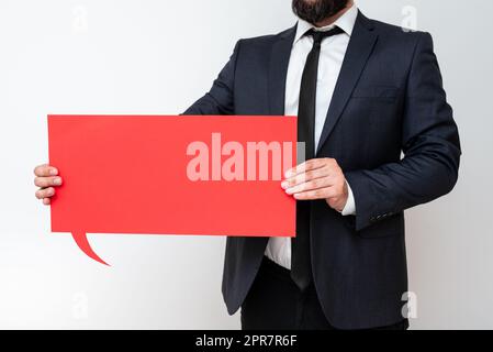 Businessman Holding Speech Bubble With Important Messages. Man In Suit Presenting Crutial Informations On Dialogue Balloon. Gentleman Showing Recent Updates On Paper. Stock Photo