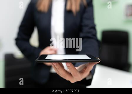 Businesswoman Holding Tablet And Presenting Important Message. Woman Having Phone In Hands And Showing Crutial Information. Executive Displaying Recent Updates. Stock Photo