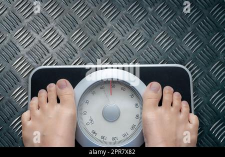 Top view of feet on weighing scale. Women weigh on a weight balance scale after diet control. Healthy body weight. Weight and fat loss concept. Weight measure machine. Body Mass Index or BMI concept. Stock Photo