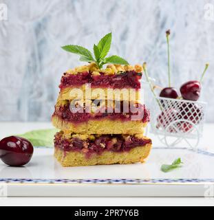 Square slices of cherry crumble lie in a stack on a white board Stock Photo