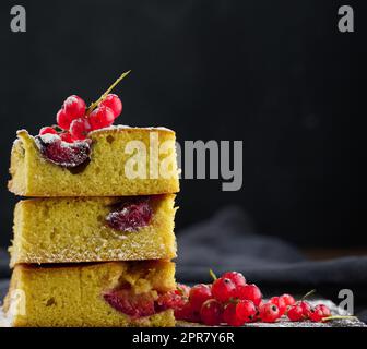 A stack of square slices of baked plum biscuit cake, sprinkled with powdered sugar on top Stock Photo