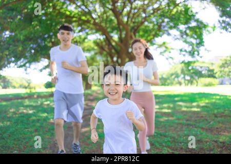 Happy little boy Jogging with parents in the city park Stock Photo
