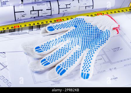 Builder's tools on the scheme of the house. Preparing to build a house. Builder's gloves and blueprints.. Stock Photo