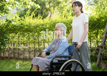 Caregiver help and care Asian senior or elderly old lady woman patient sitting on wheelchair in park, healthy strong medical concept. Stock Photo