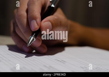 Businessman holding pen signature contract document finance investment or paperwork report on desk. Stock Photo