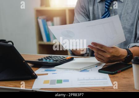 Businessman holding paperwork document graph report accounting and finance investment on desk. Stock Photo