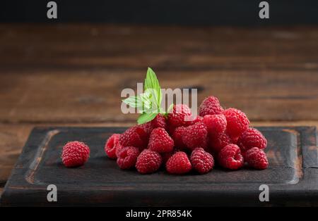 Ripe red raspberries on a brown wooden board Stock Photo