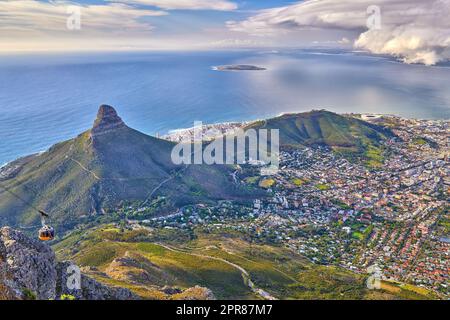 Aerial view of Lions Head mountain with the ocean and a cloudy sky copy space. Beautiful landscape of green mountains with vegetation surrounding an urban city in Cape Town, South Africa Stock Photo