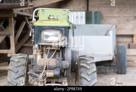 Typical heavy diesel walking tractor with trailer. Agricultural transport equipment of the countryside. Portable agricultural equipment, walking minitractor. The start system is mechanical and manual. Stock Photo