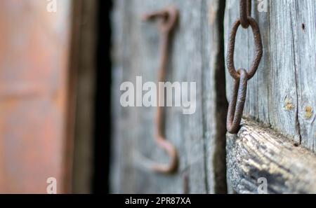 Isolated old rusty door latch on a wooden door. Close-up. Problematic weathered panels. Old wall texture background. Detail of an old wooden door with a rusty door latch. Stock Photo