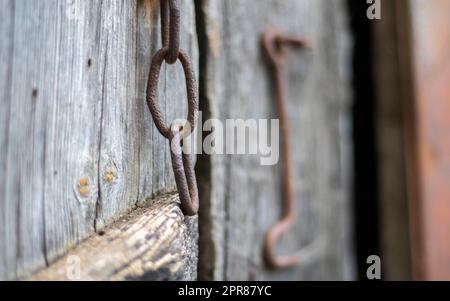 Isolated old rusty door latch on a wooden door. Close-up. Problematic weathered panels. Old wall texture background. Detail of an old wooden door with a rusty door latch. Stock Photo