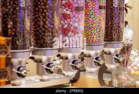 Colorful variety of fruit candies in plastic tubes in a candy store. Jelly beans for sale in the store. Colorful chewing gum balls in a pastry machine. Selective focus. Stock Photo