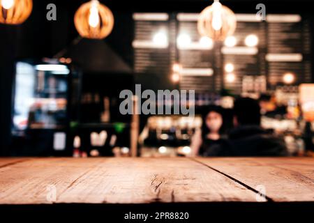 Background with wooden old deck table in front of blurred in bar or restaurant Stock Photo