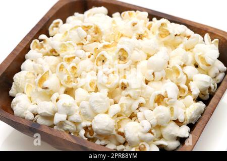 Popcorn in wooden bowl on white background, Side view, Close up Stock Photo