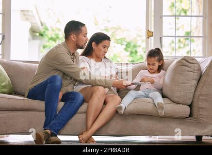 Time to give it back. Shot of a young couple taking a digital tablet away from their daughter at home. Stock Photo