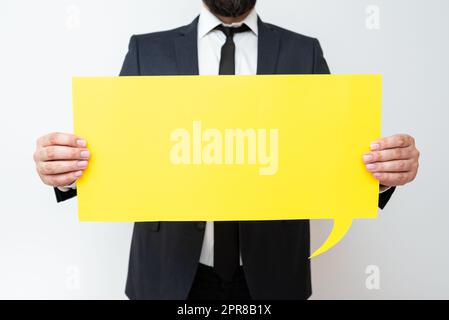 Businessman Holding Speech Bubble With Important Messages. Man In Suit Presenting Crutial Informations On Dialogue Balloon. Gentleman Showing Recent Updates On Paper. Stock Photo