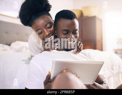 Lets take a look. Shot of a young couple using a digital tablet together at home. Stock Photo