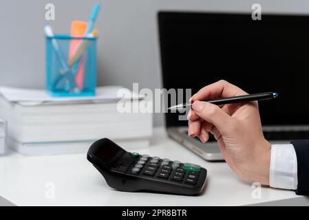 Businesswoman Pointing With Pen On Important Messages On Desk With Calculator. Executive In Suit Presenting Crutial Informations. Woman Showing Critical Announcements. Stock Photo