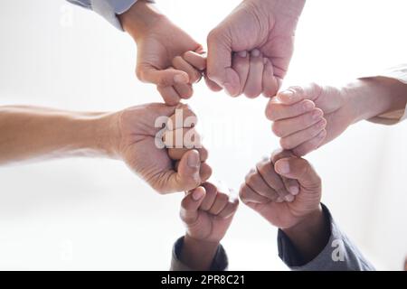 There is more power in unity than division. Shot shot of a group of unidentifiable businesspeople joining their fists together in a unity. Stock Photo