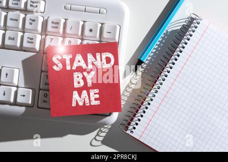 Text sign showing Stand By Me. Business concept Be always around myself there count on someone all the time Important Messages Written On Note On Desk With Pen, Notebook And Keyboard. Stock Photo