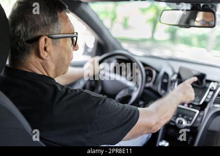 Senior behind the steering wheel using gps navigation Stock Photo