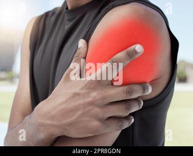 Closeup of sports man suffering from an inflamed shoulder injury. Athletic, active athlete holding and rubbing his sore arm with glowing red cgi. Overworking muscles causes tension, cramp or sprain Stock Photo