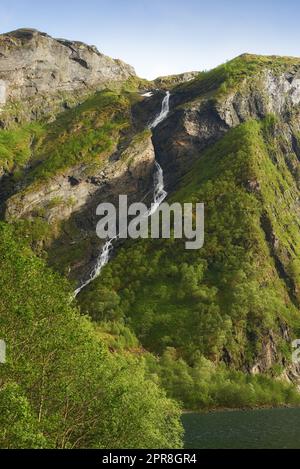 Mountain spring water flowing through a jungle thicket on an island, nature in its purest form. Beautiful landscape of clean river water coming down a rocky hill on a summer day outdoors in nature. Stock Photo